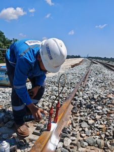 Technician performing MPI inspection on rail weld during ECRL project in Malaysia